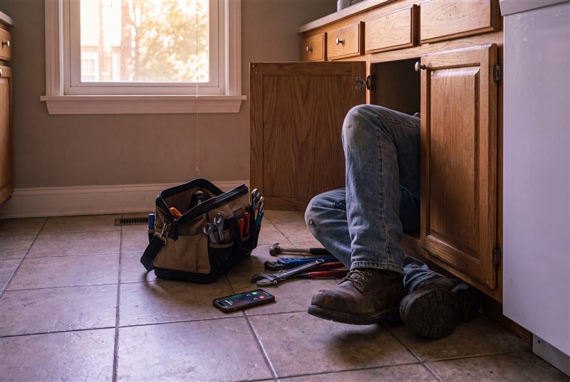 Plumber working under a kitchen sink